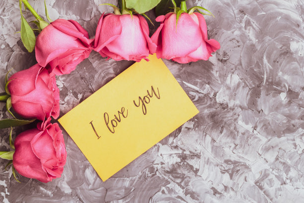 情人节的概念。灰色混凝土背景上的红玫瑰和一张写着“我爱你”的明信片图片下载