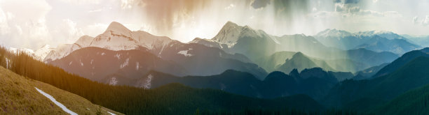 壮丽的喀尔巴阡山脉壮丽的全景，覆盖着常青的森林在薄雾宁静的早晨或晚上在黑暗多云的天空。远处的山顶上覆盖着积雪。图片下载