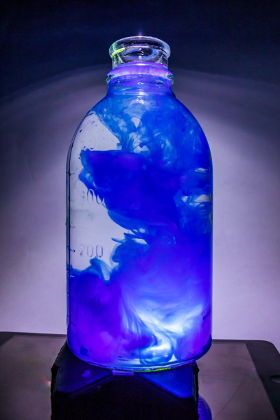 这是一个透明花瓶的艺术照片，里面有一株植物，有清水和蓝色的墨水图片下载