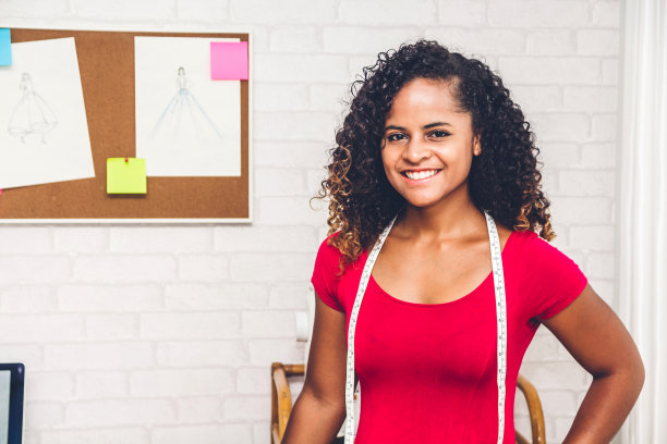 微笑的非洲裔美国黑人女性时装设计师附近的人体模型和衣服在工作室图片下载