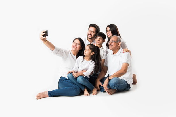 印度一家三代人坐在白色背景上用智能手机自拍。有选择性的重点图片下载