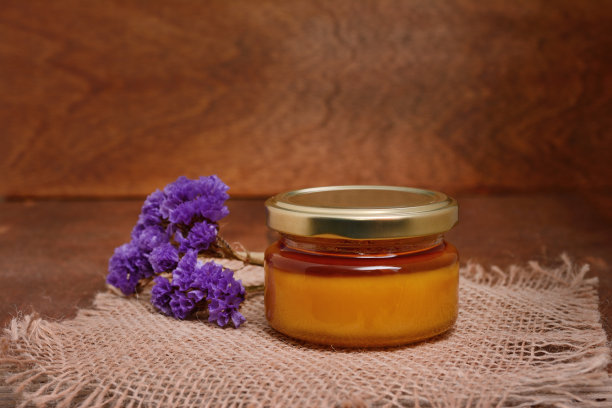 一罐蜂蜜和一根薰衣草枝放在一张粗糙的木桌上图片下载