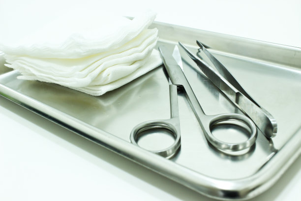 纱布，剪刀和镊子在不锈钢托盘隔离在白色背景图片下载