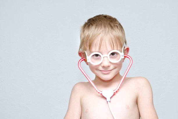 可爱的男孩戴着眼镜和语音镜扮演医生。肖像图片下载
