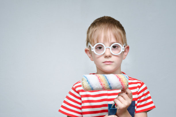 严肃的男孩戴着眼镜，拿着画轴上色。室内装修图片下载