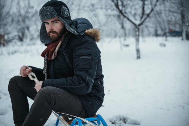 一个年轻人在下雪的冬天拉雪橇的肖像图片下载
