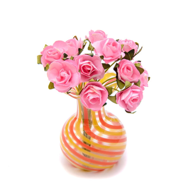 一束粉红色的人造玫瑰放在一个微型玻璃花瓶里图片下载