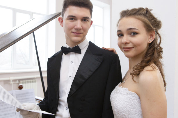 年轻漂亮的夫妇在晚礼服和礼服大衣摆出优雅的方式在一个经典的风格图片下载