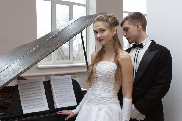 年轻漂亮的夫妇在晚礼服和礼服大衣摆出优雅的方式在一个经典的风格图片下载