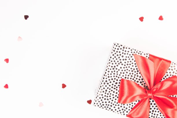 礼盒与红色缎子蝴蝶结在白色背景与闪光的五彩纸屑。节日的概念。孤立。图片下载