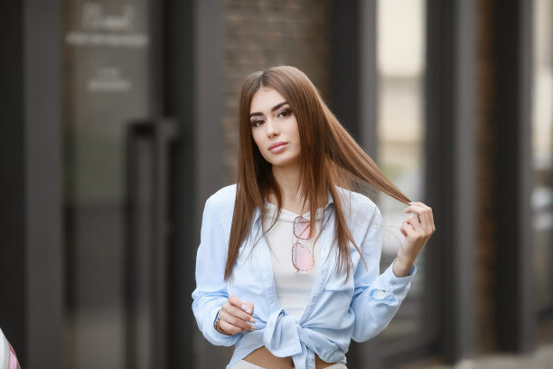 一个年轻的微笑美丽的亚洲女人的肖像与长黑发。生活方式图片的模特穿着白色t恤和蓝色的牛仔裤与刺绣图片下载