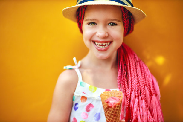 快乐的小女孩吃冰淇淋在黄色的背景图片下载