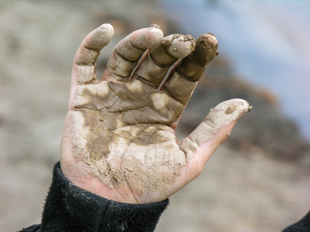 手掌——小快乐的孩子的手掌上覆盖着干燥的泥土，粘土，在挥手。概念、背景图片下载