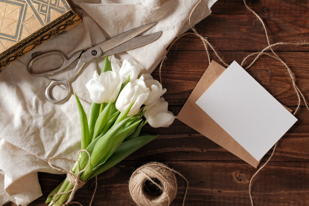 春天一束白色的郁金香花，空白的纸卡，剪刀，麻线在质朴的木桌上。妇女节作文就平铺式，上面看。图片下载
