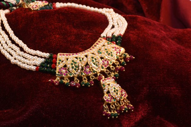 奇特的金色“Jadau”吊坠与彩色梨和珠子特写微距图像在红色背景。图片下载