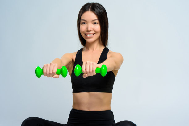 亚洲女孩用绿色哑铃练习。图片下载