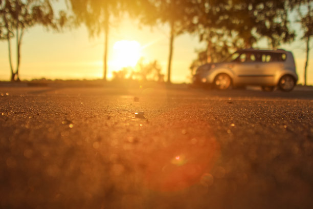 深晨曦与亮点在橙色的阳光在夏季的道路上的树林上模糊的背景灯和汽车图片下载