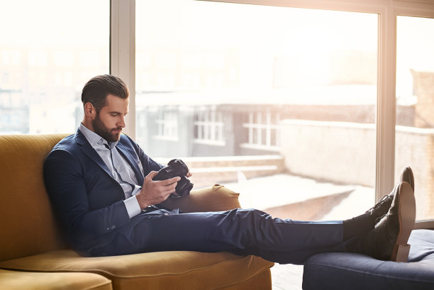 感觉舒服……年轻迷人的男人在时尚西装看着照片，感觉轻松的办公室图片下载