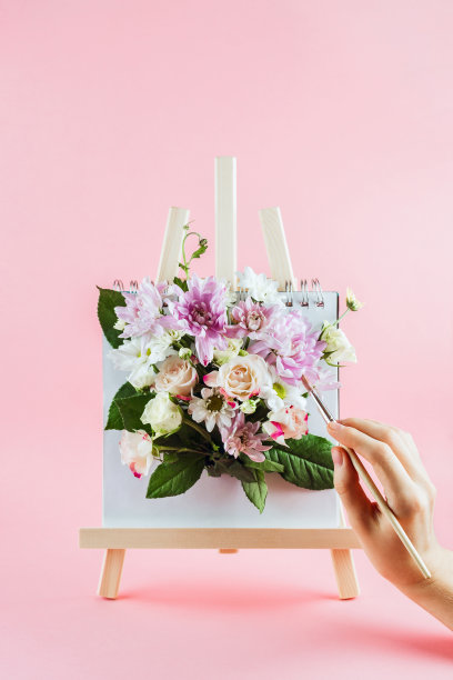 女人的手拿着画笔，在画架上画着花图片下载