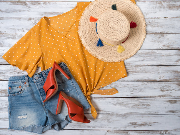 女装、配饰、鞋类(皮骡跟鞋、牛仔短裤、黄色圆点衬衫、草帽)。时尚套装，春夏系列。购物的概念。平躺，从上面看图片下载