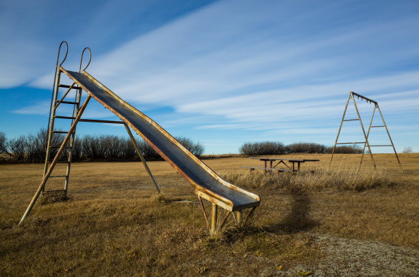 在加拿大阿尔伯塔的某个地方，生锈的老草原秋千和滑梯图片下载