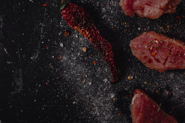 新鲜生猪肉肉与香料，盐和胡椒在一个深色的石头背景，空白的文字，复制粘贴，俯视图图片下载