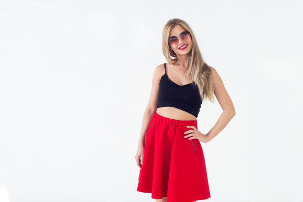 可爱的年轻女模特抚摸着长长的金发，面带微笑，穿着清新的夏装，带着圈太阳镜正面视图图片。图片下载