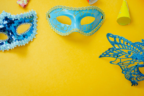 桌面俯瞰航拍图像的美丽多彩的狂欢节季节或照片亭prop Mardi Gras背景。平铺物体彩色的蓝色面具用装饰派对在黄色的纸上。空间的文本图片下载