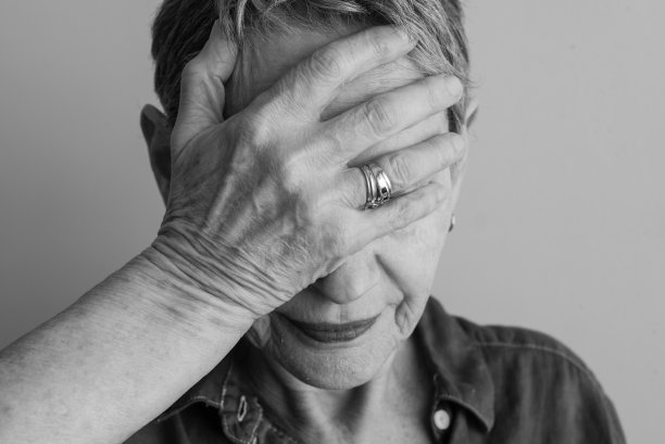 黑色和白色的老龄妇女的特写与手覆盖的脸图片下载