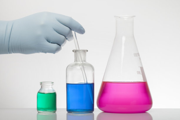 一只手在实验室手套混合化学。实验瓶中的液体。科学的生化实验室。五颜六色的液体。隔离在白色背景下，一组试管。图片下载