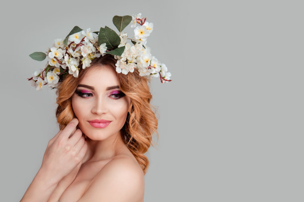 美丽的年轻女子戴着花头带微笑的手触摸脸图片下载