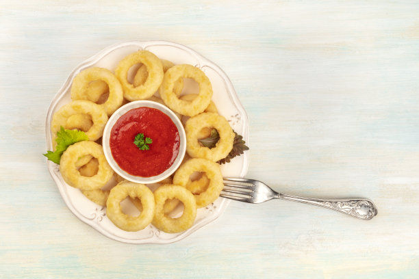 头顶上的一张照片是一盘鱿鱼圈，上面有红酱、叉子和复制空间图片下载