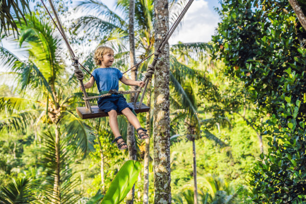 一个男孩在丛林上空荡秋千，巴厘岛图片下载