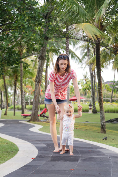 妈妈教宝宝走路，在热带度假胜地户外偷拍照片，家庭度假理念图片下载