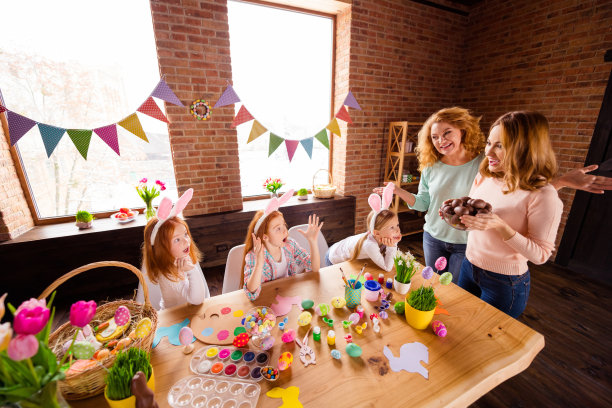 近距离的照片令人惊讶的好吃的三个小女孩儿童节惊奇的品尝巧克力蛋两个妈妈瞧，带来礼物高兴的礼物可爱的桌子满工艺坐大木头桌子地板图片下载