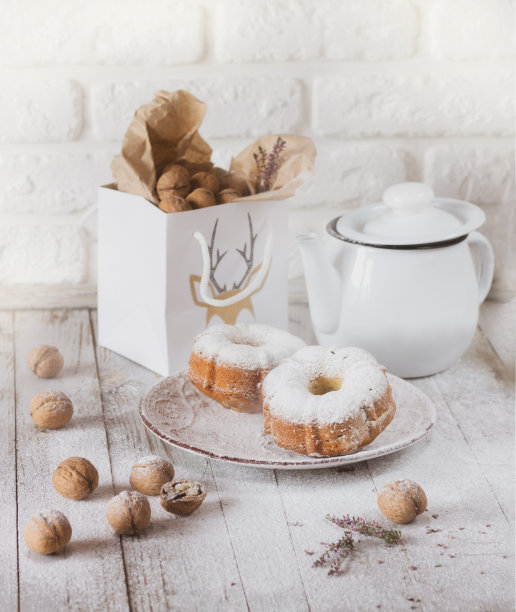 松饼、坚果和茶壶放在白色的桌子上图片下载