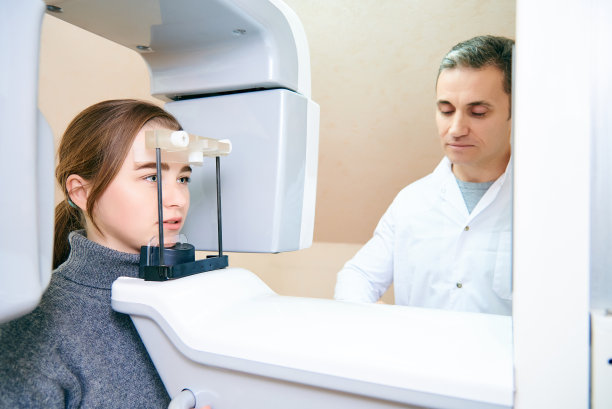 一个女病人站在一个断层照相机上，一个医生在控制面板附近图片下载