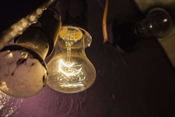 在涂了漆的水泥墙的背景上，闪烁着又脏又旧的灯泡图片下载