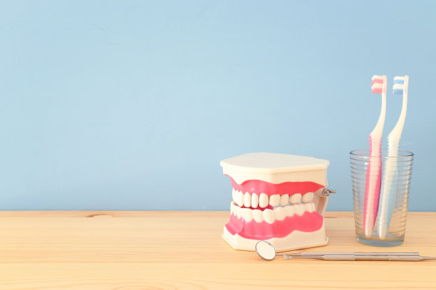 牙科医生使用的牙科保健工具和诊所的塑料牙齿模型。木制的蓝色背景。图片下载