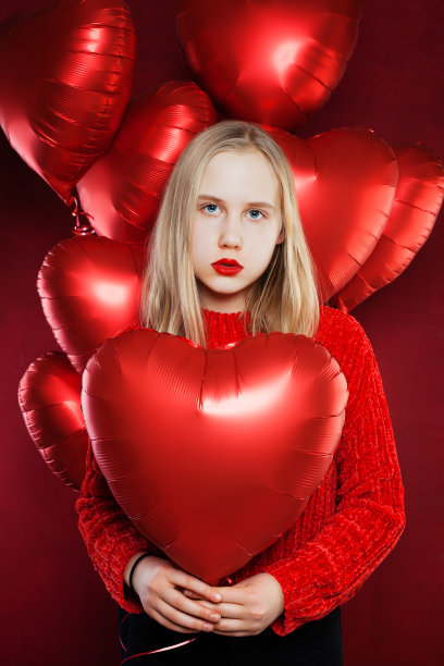 小女孩捧着气球，红着心。情人节人和情人节的概念图片下载
