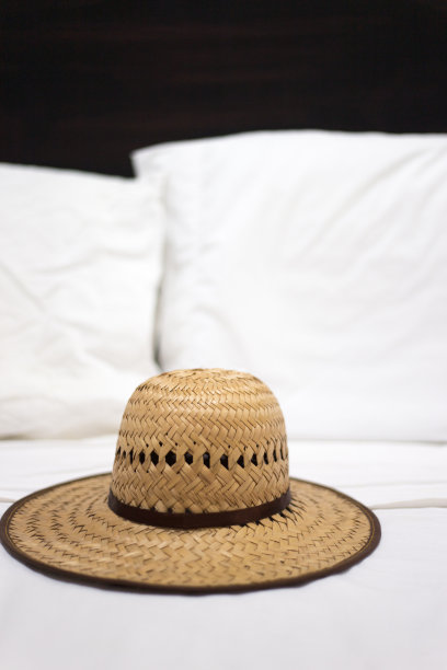 热带田园:白色床单上的草帽图片下载
