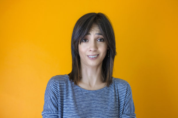 面部表情：不以为然的棕色头发年轻女人的头像，黄色背景图片下载