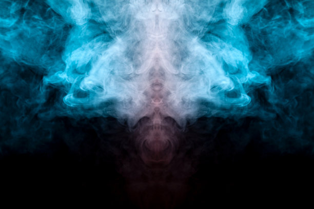 在恐怖电影中黑色孤立的背景上，绿色、蓝色和粉色烟雾形成的幽灵脸的神秘图案，有着大眼睛和张着的嘴，营造出一种恐惧的感觉。图片下载