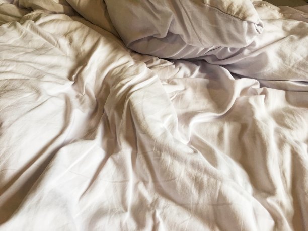 早上醒来后，皱巴巴的白软毯子铺在床上。图片下载