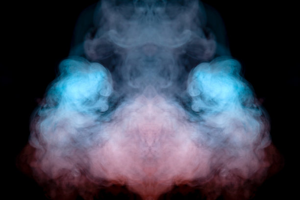 在恐怖电影中黑色孤立的背景上，绿色、蓝色和粉色烟雾形成的幽灵脸的神秘图案，有着大眼睛和张着的嘴，营造出一种恐惧的感觉。图片下载