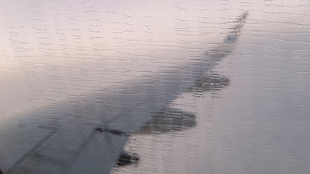 玻璃飞机和雨滴。在云层上飞行。从飞机的窗口我们可以看到模糊的机翼。抽象的照片。图片下载