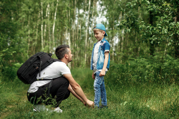 一个背着背包的男人，一个父亲和他的儿子在徒步旅行，在树林里散步。家庭生活，与家人一起消遣，养育孩子。图片下载