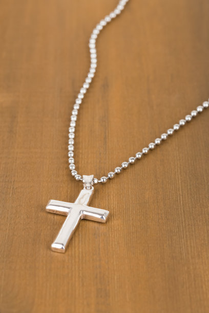 木制背景上的银十字架和项链图片下载