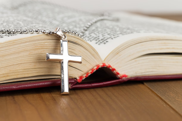 木桌上的银十字架项链和打开的圣经图片下载