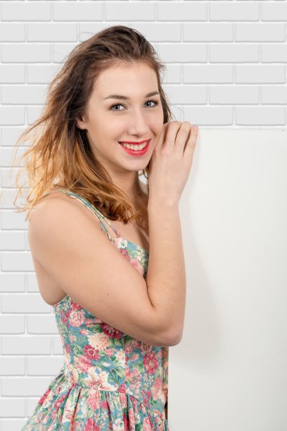 快乐微笑的年轻女子显示与copyspace空空白招牌图片下载